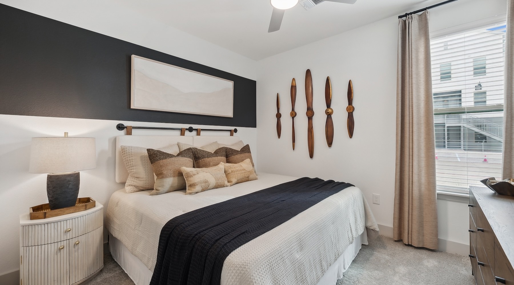 a bedroom with a nightstand, dresser and a window