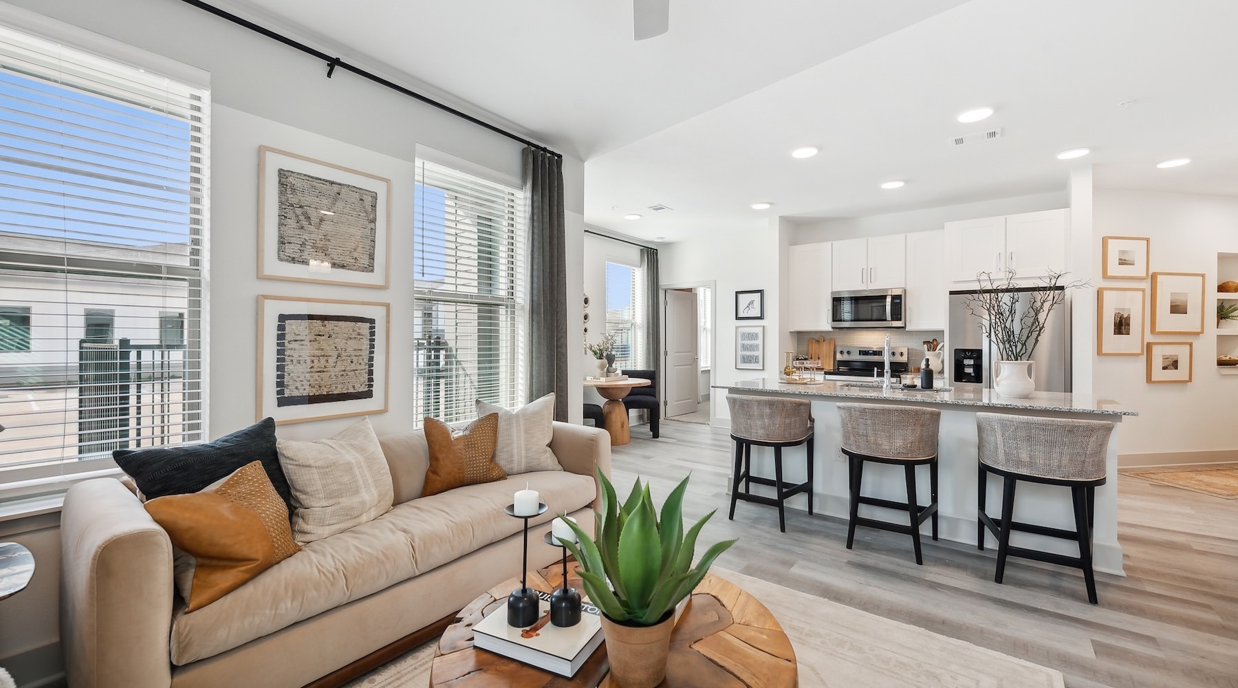 Model living room at Alta Trails Apartments for rent in Bastrop, TX, featuring wood grain floor paneling.