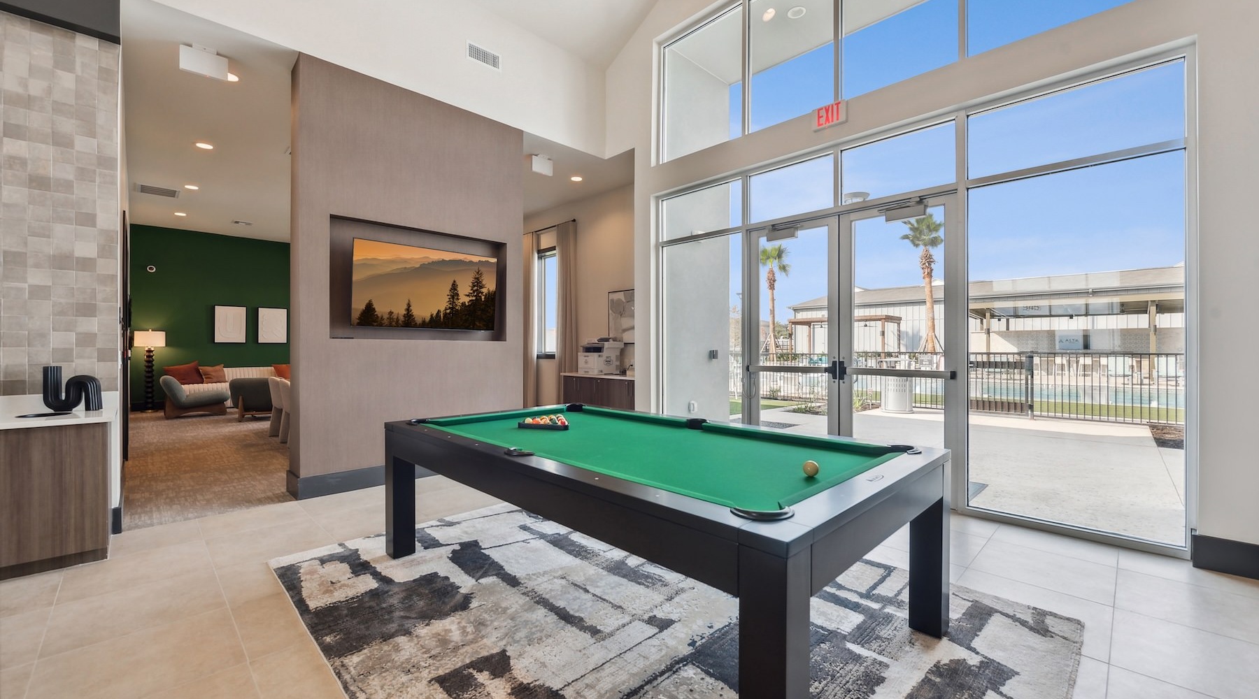 a clubhouse room with a pool table and a large window